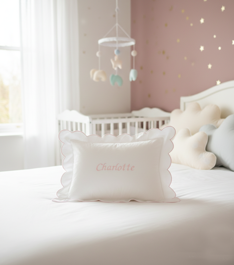 Baby room with crib, pillows, and a mobile in a softly lit room. Personalised baby pillowcase with embroidered name in soft cotton, luxury newborn keepsake gift UK