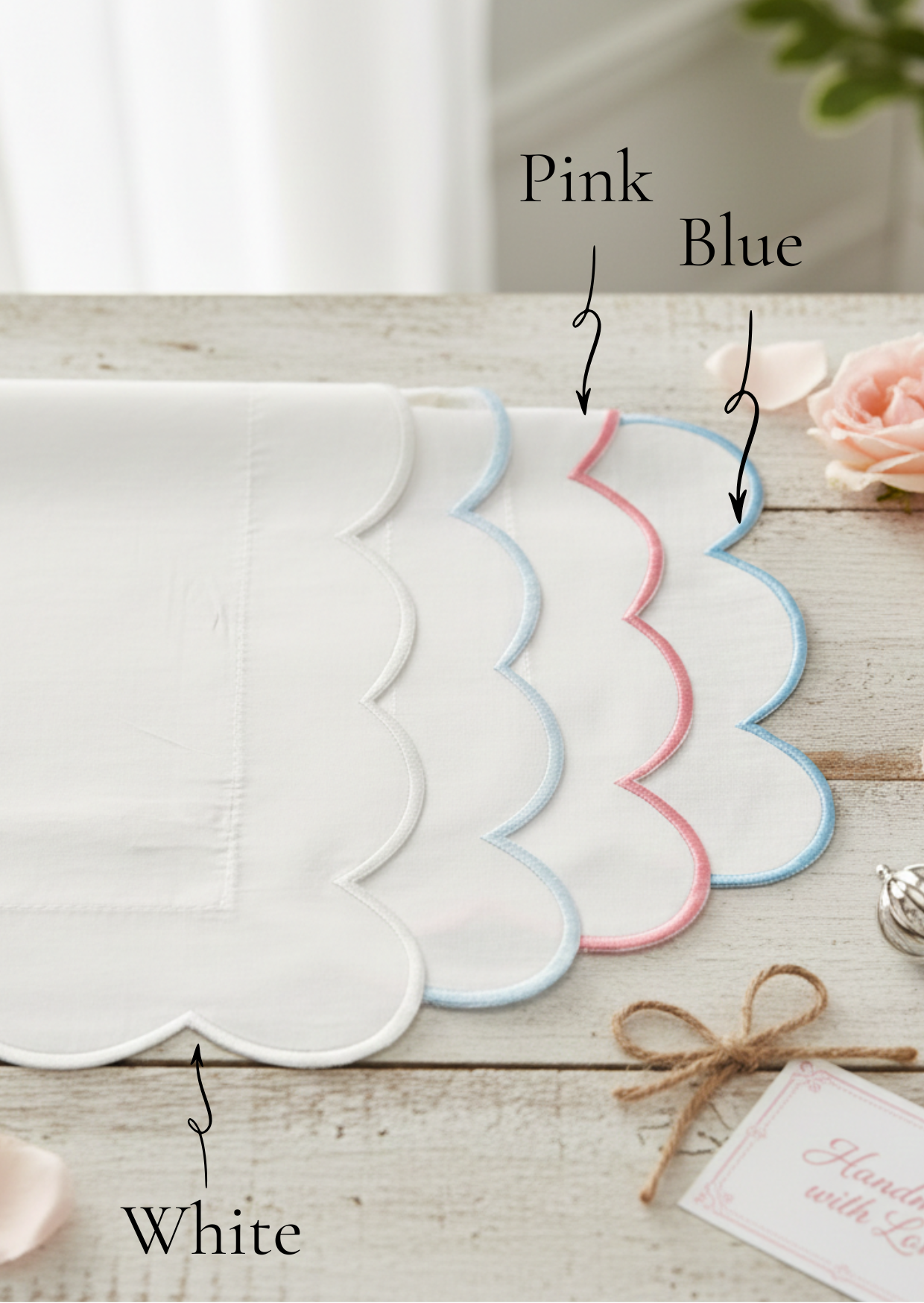 Set of scalloped Baby pillowcases in white, pink, and blue on a wooden surface.