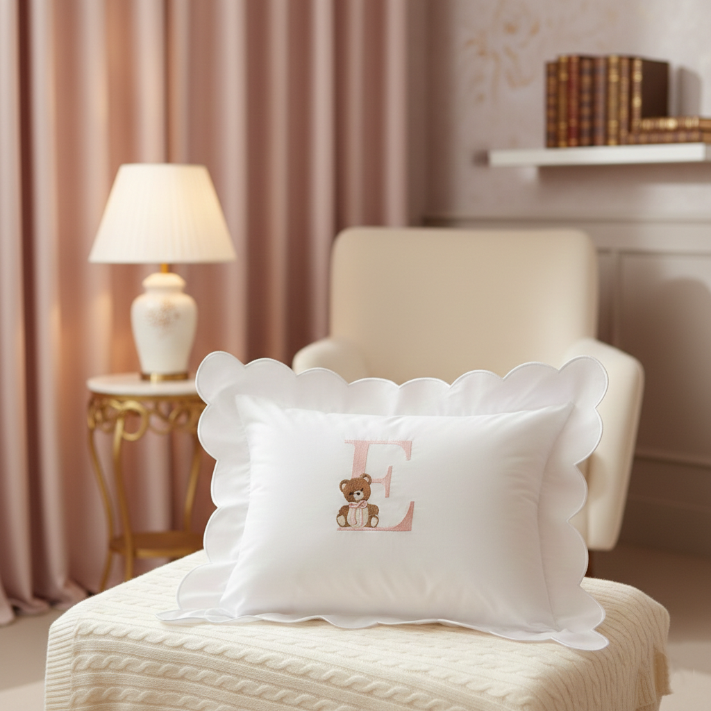 Personalised pink E monogram baby pillow with embroidered teddy bear and white scalloped edge	