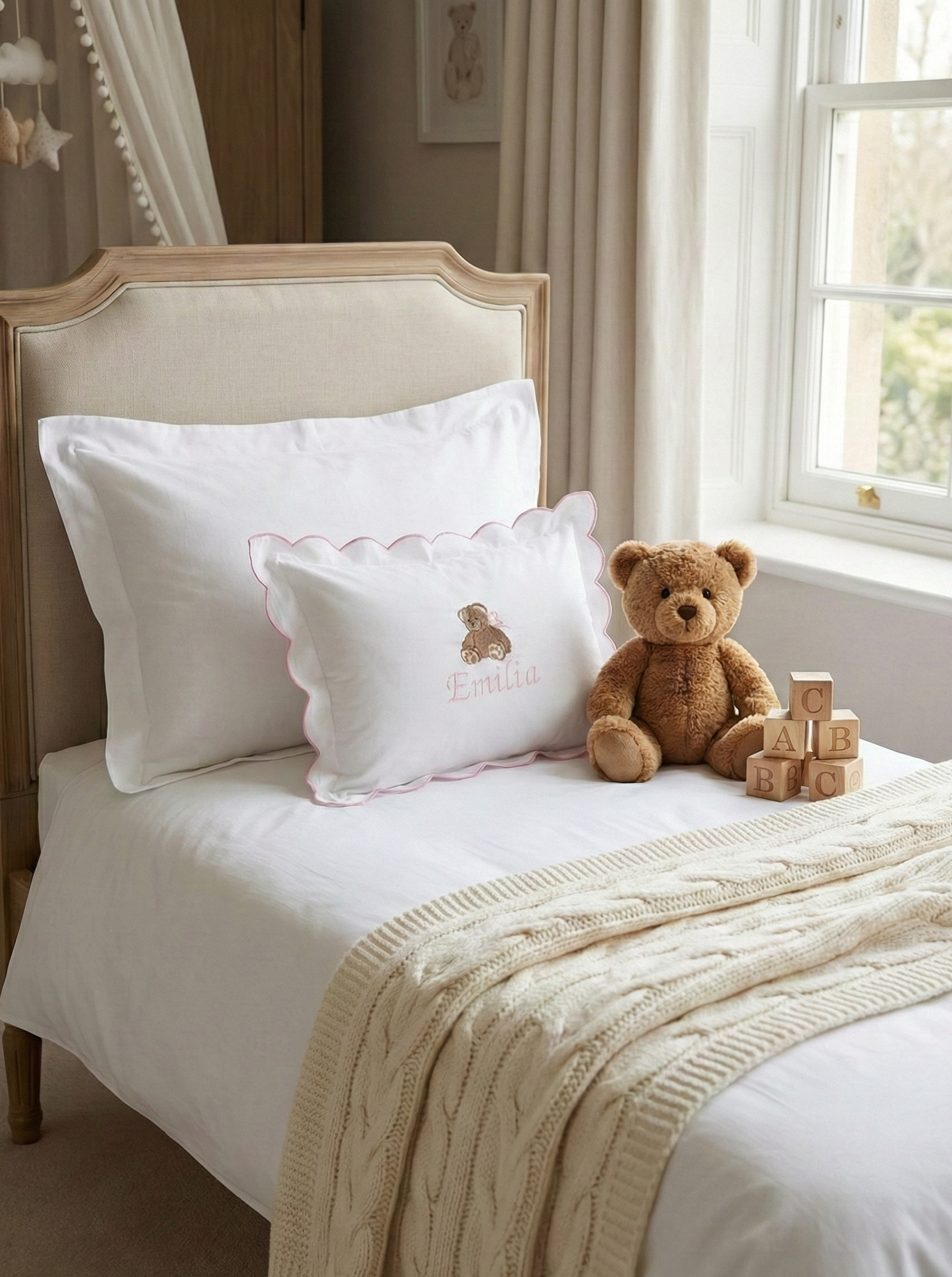 Children's bedroom with a bed, teddy bear, and blocks near a window. Personalised baby pillowcase with embroidered name in soft cotton, luxury newborn keepsake gift UK